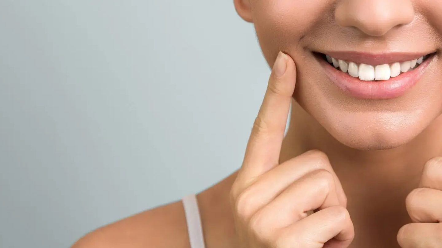 Mujer señalando su sonrisa sana